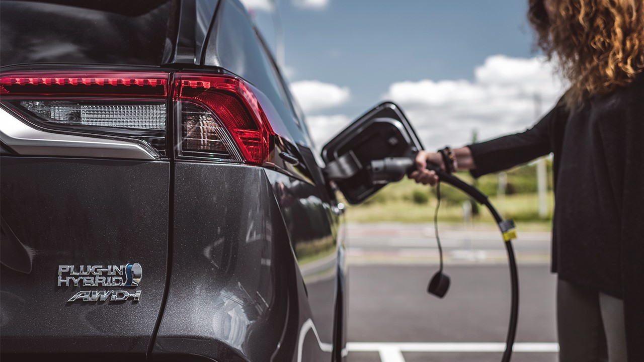 Woman plugging Toyota RAV4 plug-in hybrid