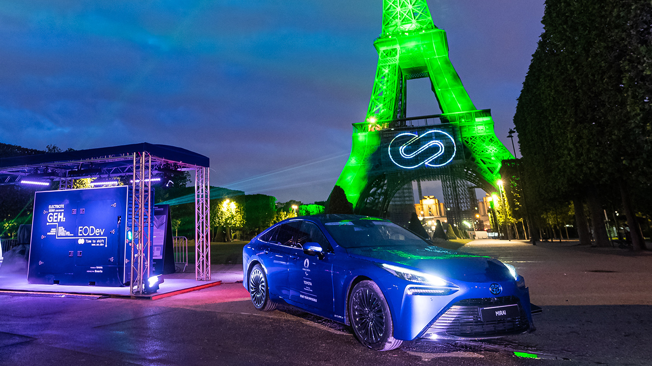 Toyota Mirai in front of Eiffel tower illuminated en powered by renewable hydrogen from Energy Observer Developments’ generator with Toyota fuel cells