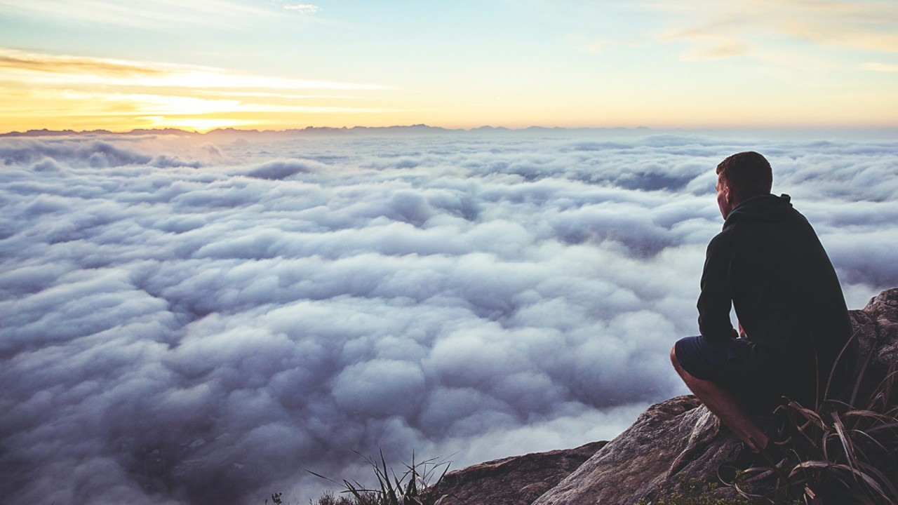 Man looking at the horizon from a mountaintop