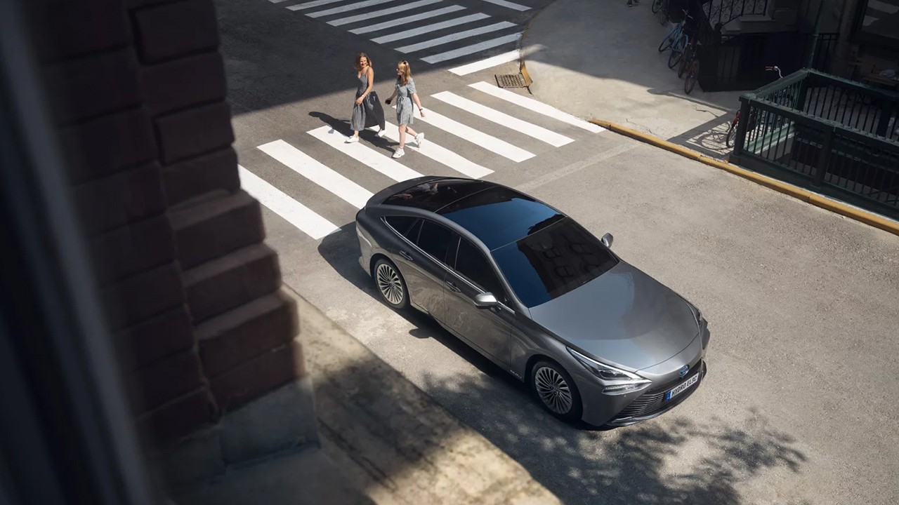 Hybrid Toyota car on a street with pedestrians